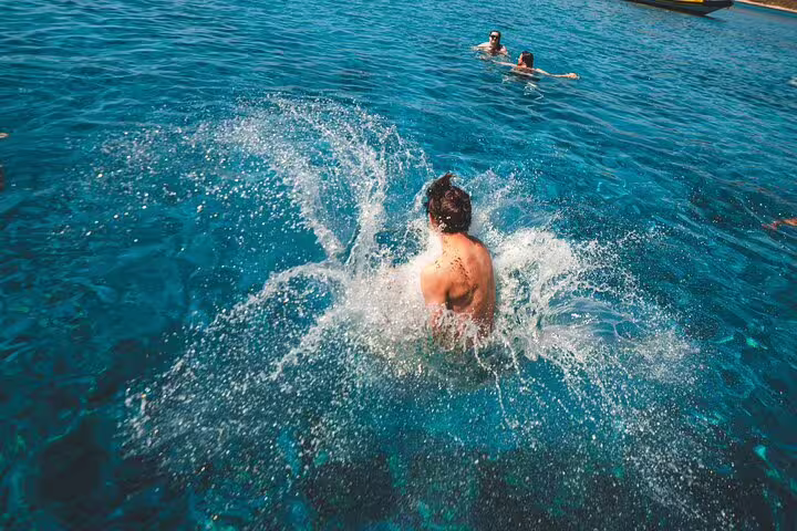 Guest splashing into the Blue Lagoon on a 3 Islands speedboat tour, crystal-clear water swim stop