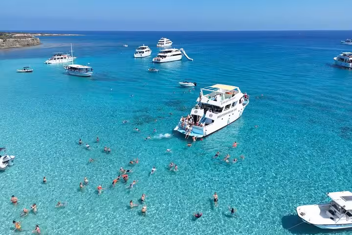 Blue Lagoon Akamas boat cruise from Paphos with water slide, swimmers in crystal-clear turquoise sea