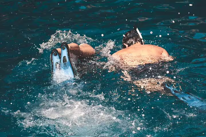 Guests snorkeling with fins in turquoise Blue Lagoon sea during the scheduled 3 Islands speedboat tour