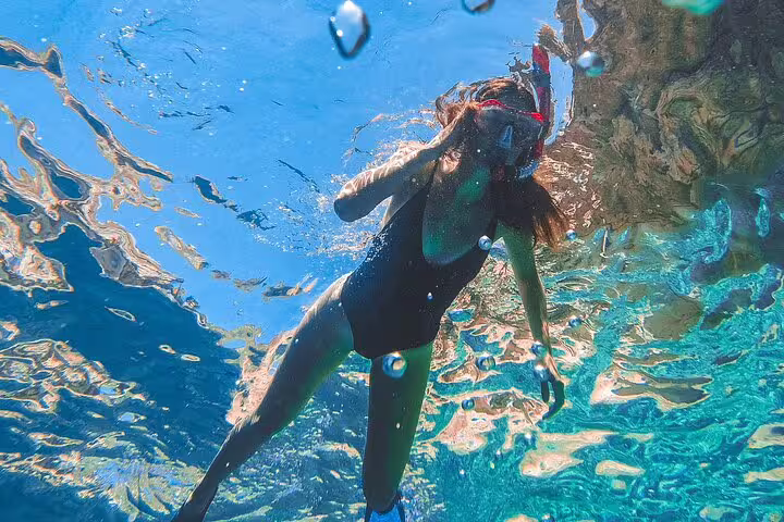 Snorkeler in crystal-clear Blue Lagoon waters on a 3 Islands speedboat tour, exploring vibrant reefs