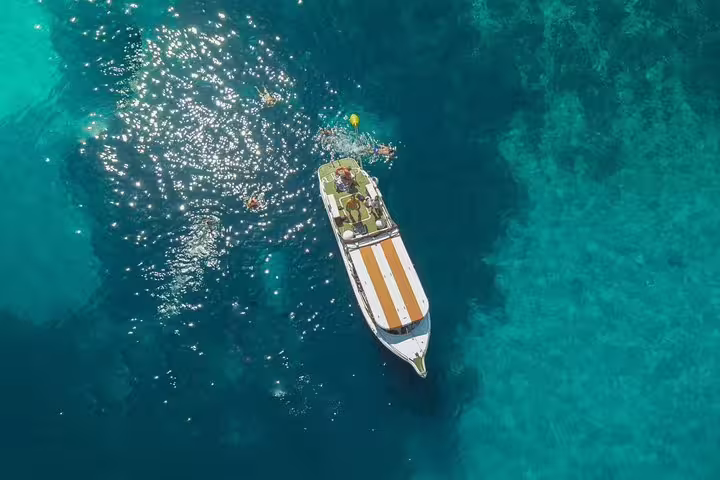 Speedboat anchored in Blue Lagoon with swimmers in crystal-clear water on the 3 Islands tour, Malta