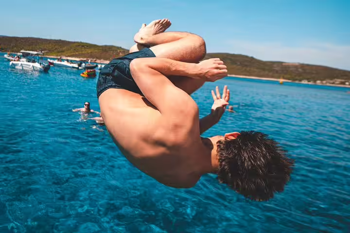 Traveler backflips into crystal-clear Blue Lagoon on a 3 Islands speedboat tour, Croatia snorkeling stop