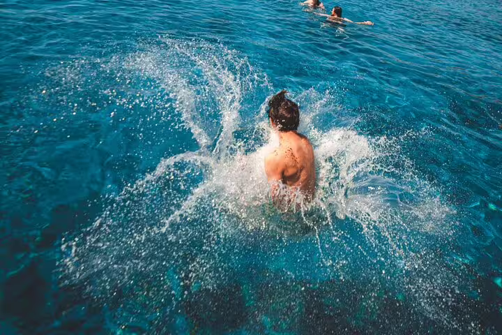 Swimmer splashing into crystal-clear Blue Lagoon water during the Blue Lagoon & 3 Islands speedboat tour from Split