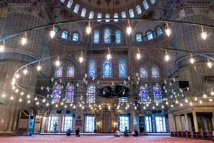 Interior view of the Blue Mosque's ornate ceiling and stained glass, featured in the Istanbul private tour for cruisers.