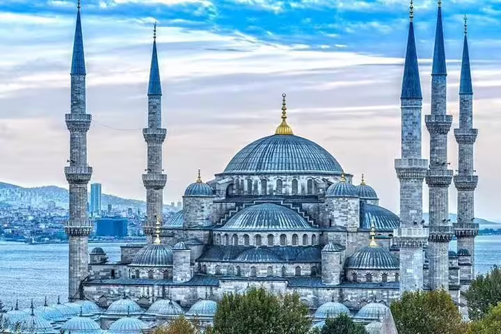 Exterior of the Blue Mosque showcasing its majestic domes and minarets against a scenic Istanbul skyline.