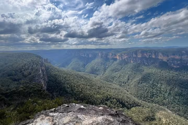 Stunning panoramic view of the Blue Mountains' lush valleys and cliffs under a dramatic sky, ideal for winery tours.