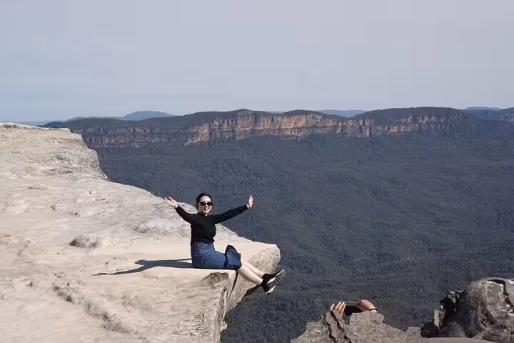 Tourist enjoying a breathtaking view from a cliff edge in the Blue Mountains, highlighting adventure and scenic vistas.