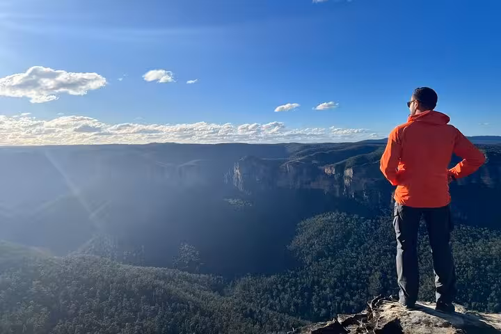 Man in orange jacket admiring breathtaking Blue Mountains vistas on a guided private tour with convenient transport.