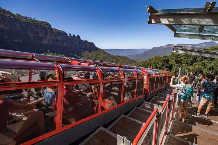 Tourists boarding Scenic Railway with breathtaking Blue Mountains backdrop, showcasing adventure on private tour.