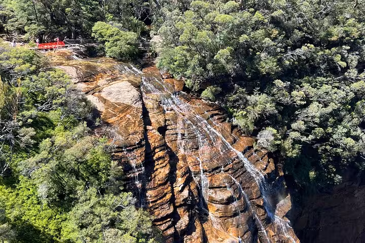 Aerial view of cascading waterfall surrounded by lush forest in Blue Mountains.