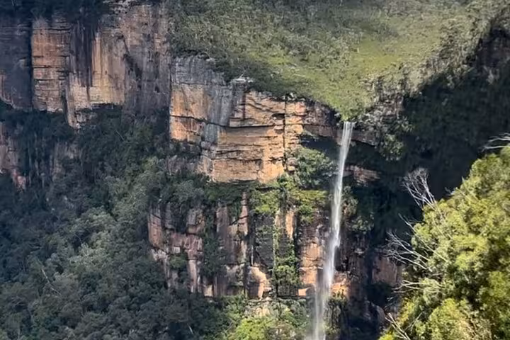 Majestic waterfall cascading down lush cliffs in Blue Mountains, perfect for private group tours exploring nature.