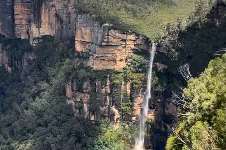 Majestic waterfall cascading down rugged cliffs in the Blue Mountains, showcasing natural beauty on a private tour.