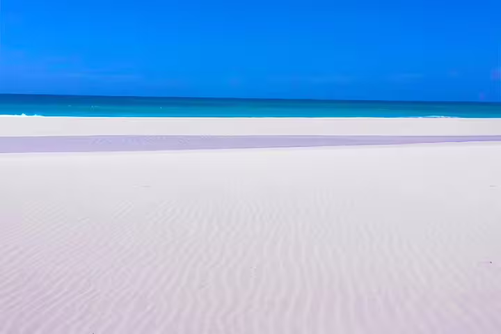 Pristine white sandy beach meeting turquoise ocean under a clear blue sky in Boa Vista adventure tour.