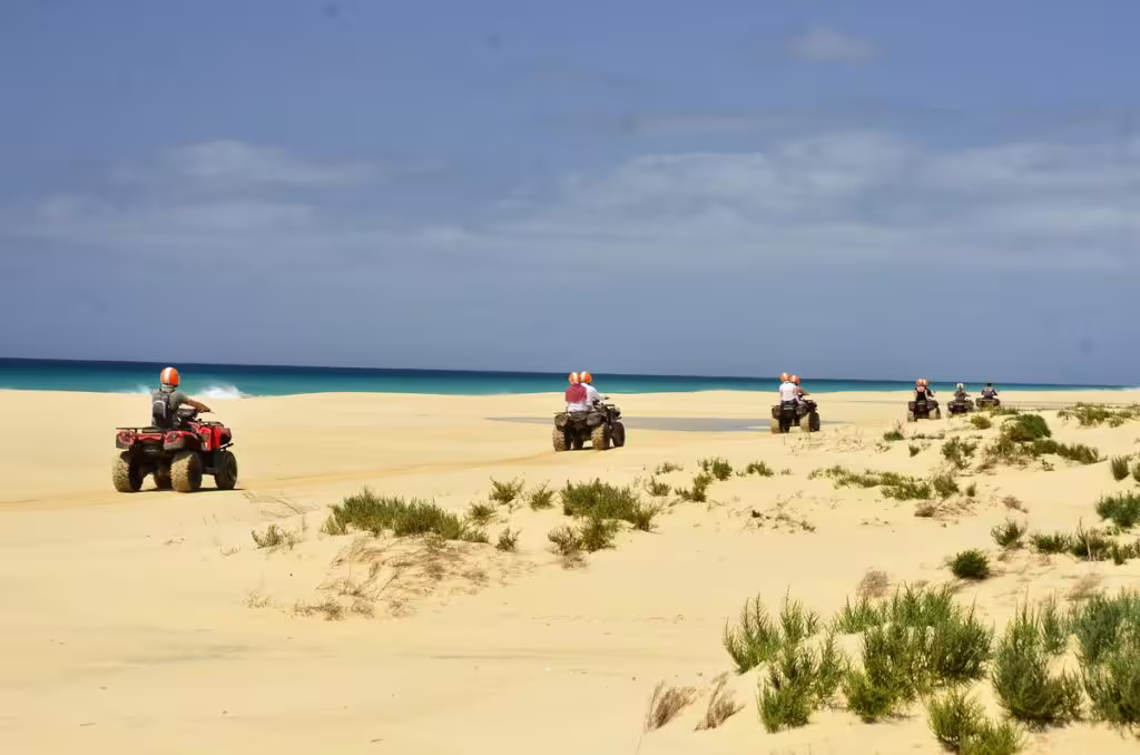 Riders on quad bikes explore the sandy terrain of Boa Vista Island's Santa Monica beach on a sunny day.