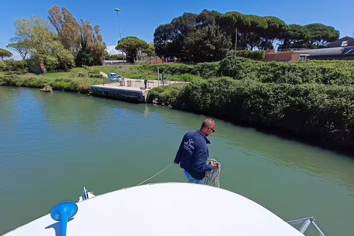 Boat captain preparing mooring line on calm canal near Ostia Antica during scenic river cruise excursion from Rome