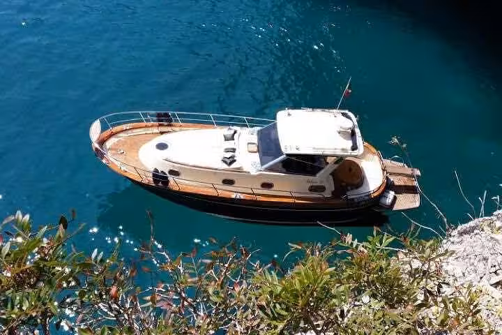 Charming boat anchored in a serene cove during a shared tour to Amalfi and Positano from Sorrento.