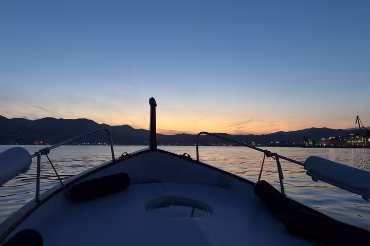 Boat cruising at sunset in La Spezia with mountains silhouetted in the distance.