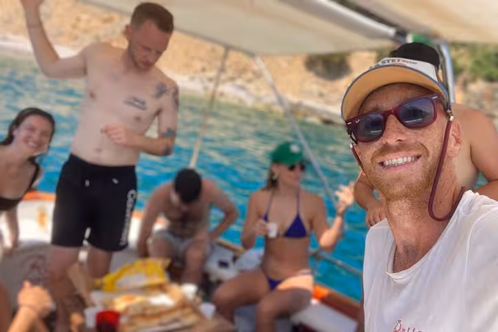 Group enjoying a lively boat tour party with snacks and drinks on the stunning waters of Cinque Terre.