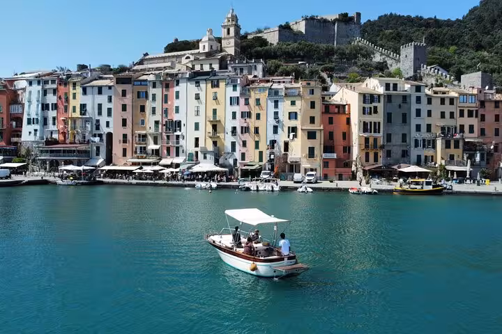 Picturesque boat cruising past vibrant Portovenere buildings and historic architecture, showcasing a dream Italian tour.