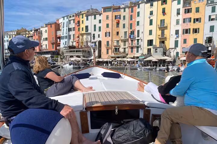 Tourists relaxing on a boat with a view of vibrant Portovenere, La Spezia, Italy.