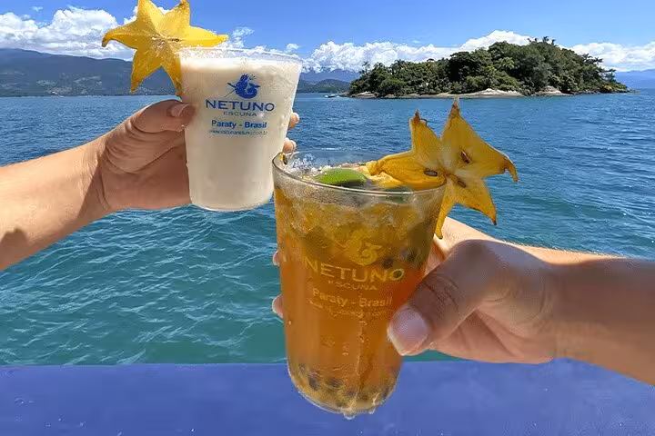 Two caipirinhas with starfruit garnish on a boat in Paraty, Brazil, with a stunning island view in the background.