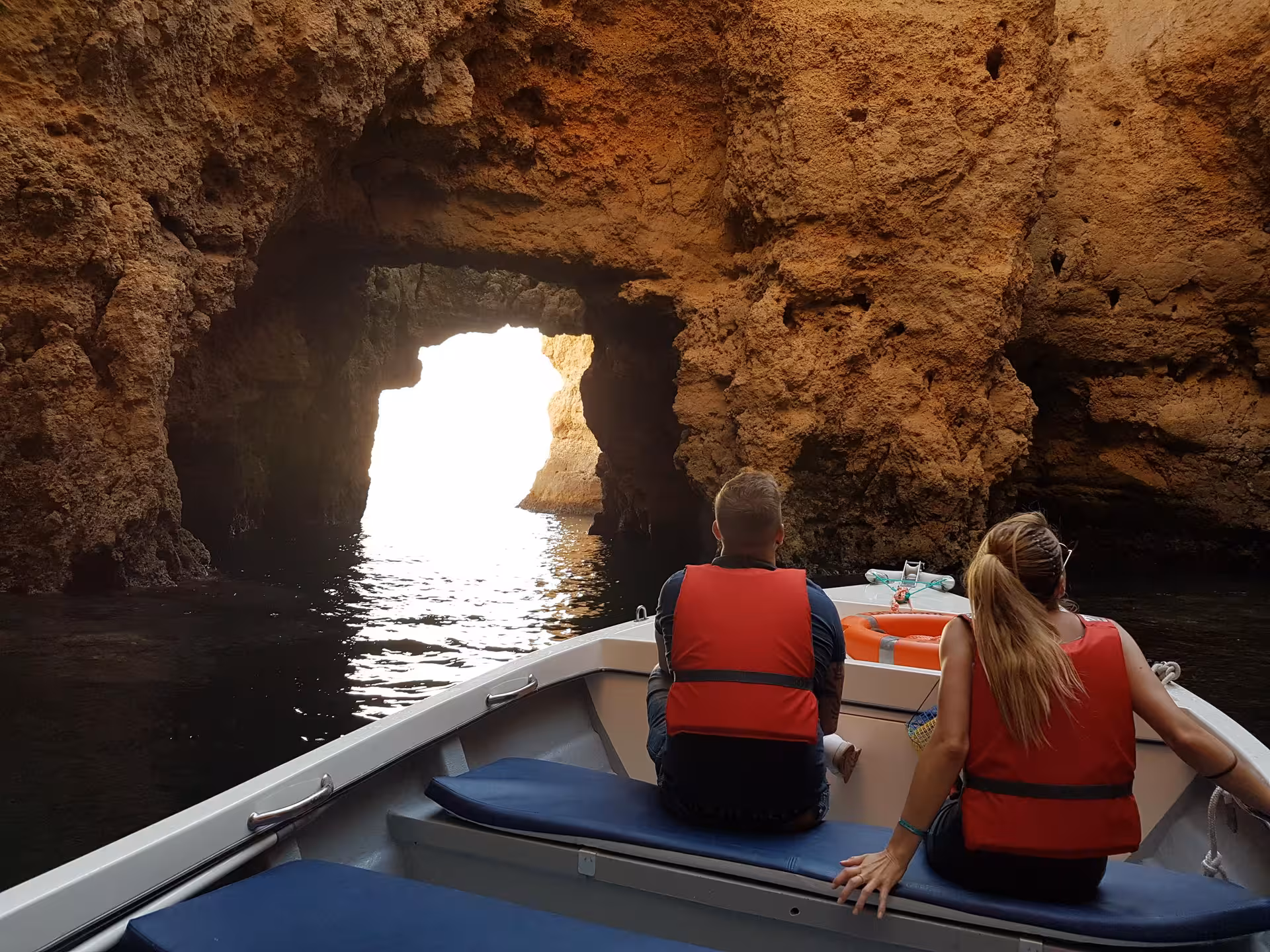 Couple on guided boat trip explores dramatic sandstone grottoes of Ponta da Piedade caves near Lagos, Algarve Portugal