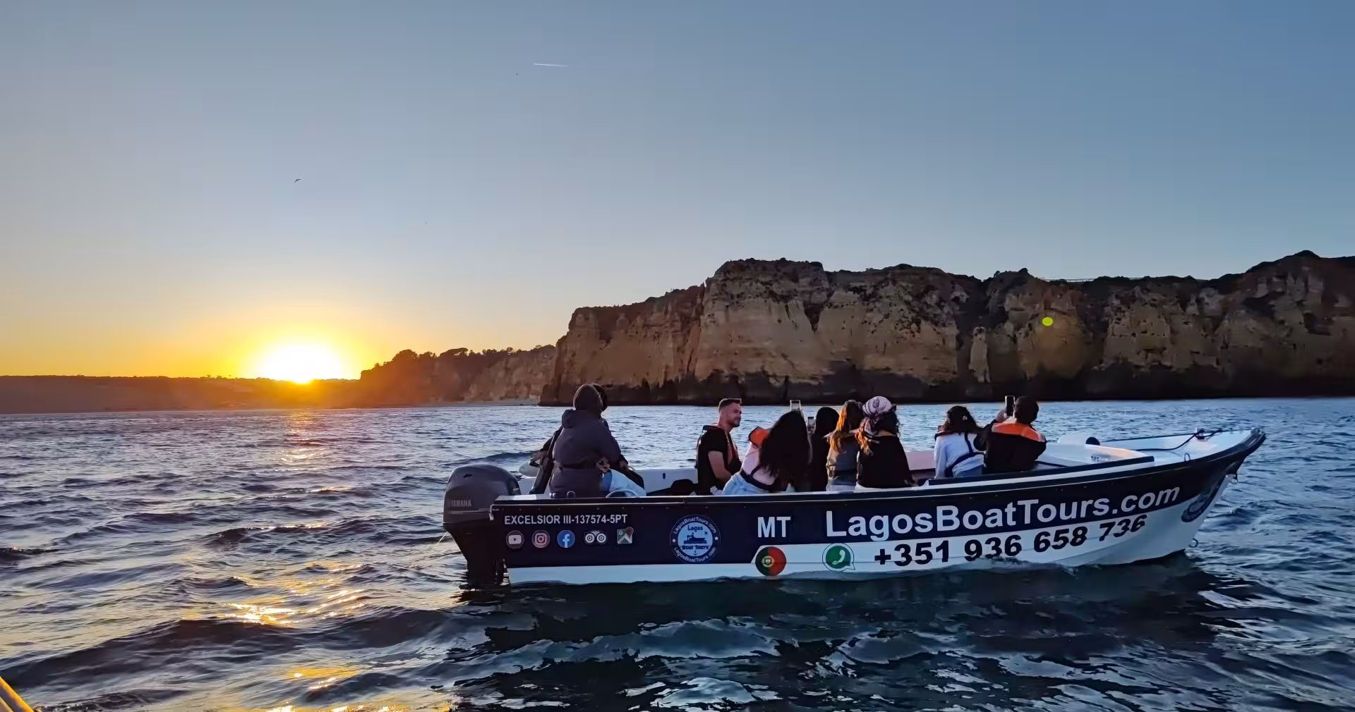 Sunset boat cruise from Lagos along Ponta da Piedade cliffs, tourists photographing golden Algarve coastline from the water