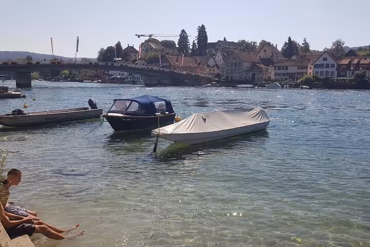 Boats moored along the scenic Rhine River in Stein am Rhein, with historic buildings in the background.