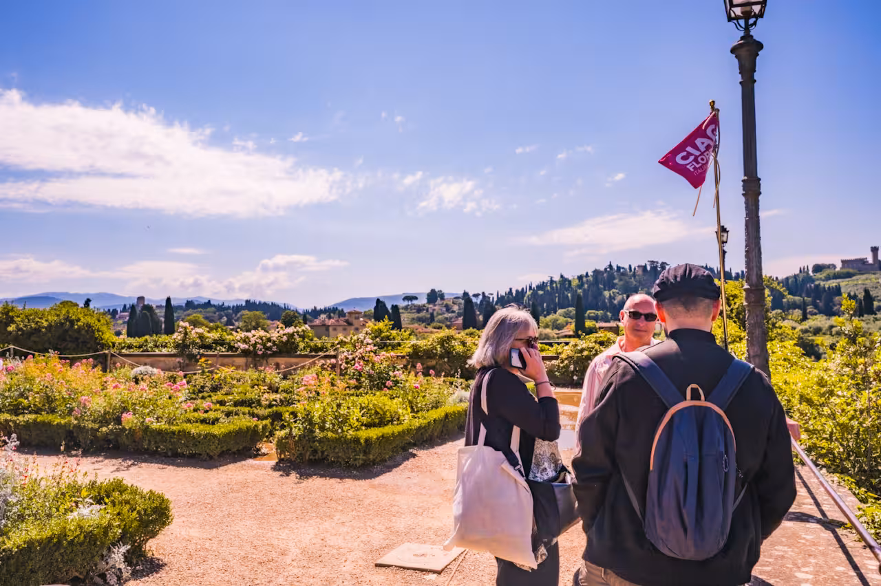 Visitors enjoying a guided tour in Boboli Gardens, overlooking the scenic Tuscan landscape under a clear blue sky.