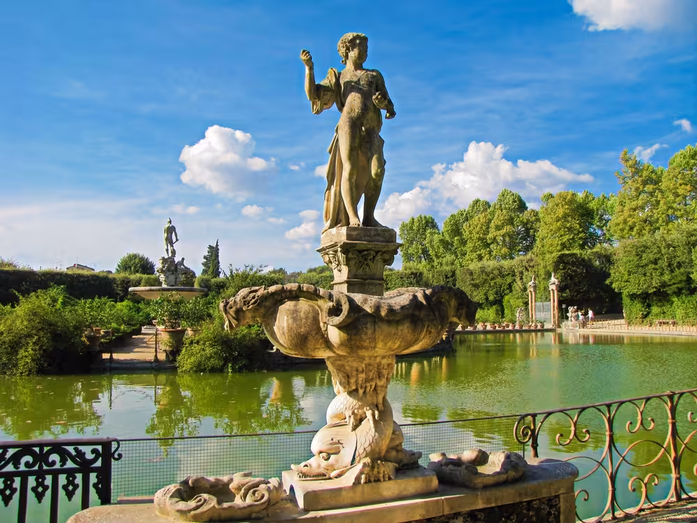Stunning statue overlooking serene pond in the lush Boboli Gardens, a highlight of the Florence tour.