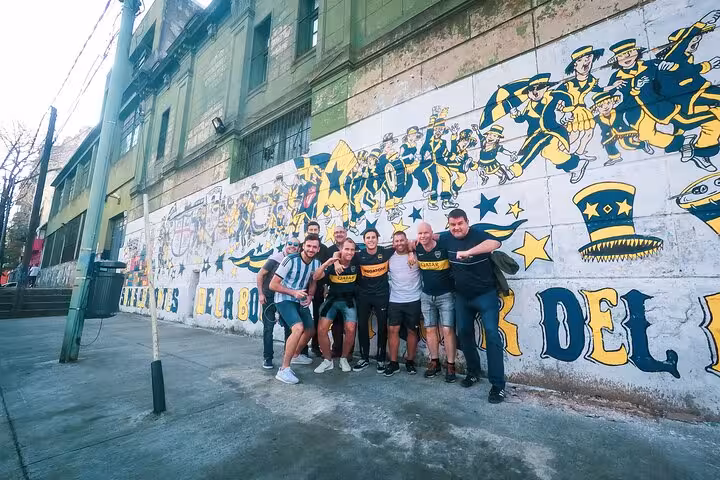 Tour group posing by Boca Juniors mural in La Boca before La Bombonera match, local guide and transport