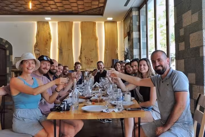 Group enjoying wine tasting at a rustic table during Bogove's Splendor tour, enhancing the waterfall adventure experience.