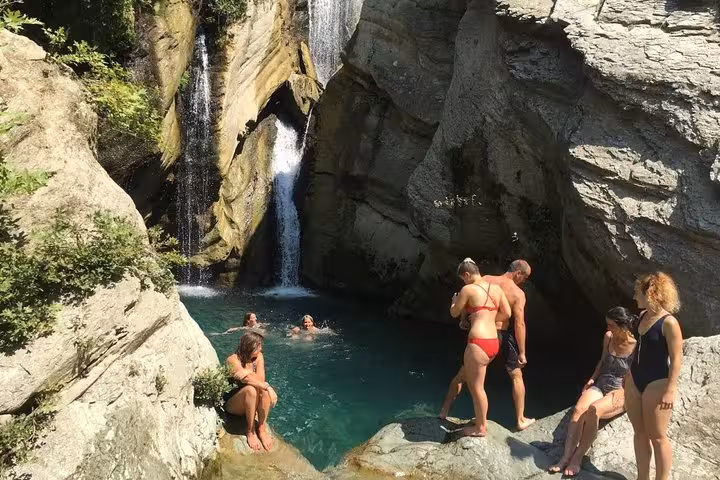 Visitors swimming and relaxing by a picturesque waterfall pool on the Bogove's Splendor adventure tour.