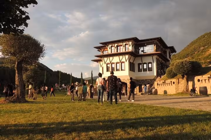 Tourists enjoy the scenic view outside a charming villa surrounded by lush greenery at sunset on a waterfall adventure tour.