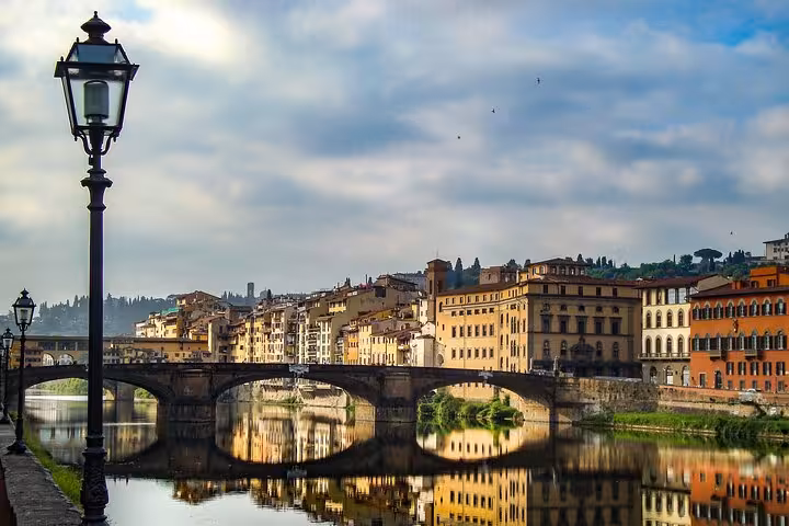 View of Florence's historic Ponte Vecchio reflected in the Arno River, a highlight on the Bologna to Florence transfer.