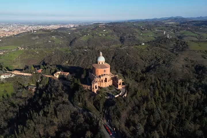 Scenic aerial view of the Sanctuary of the Madonna di San Luca perched on a hilltop near Bologna, surrounded by lush greenery.