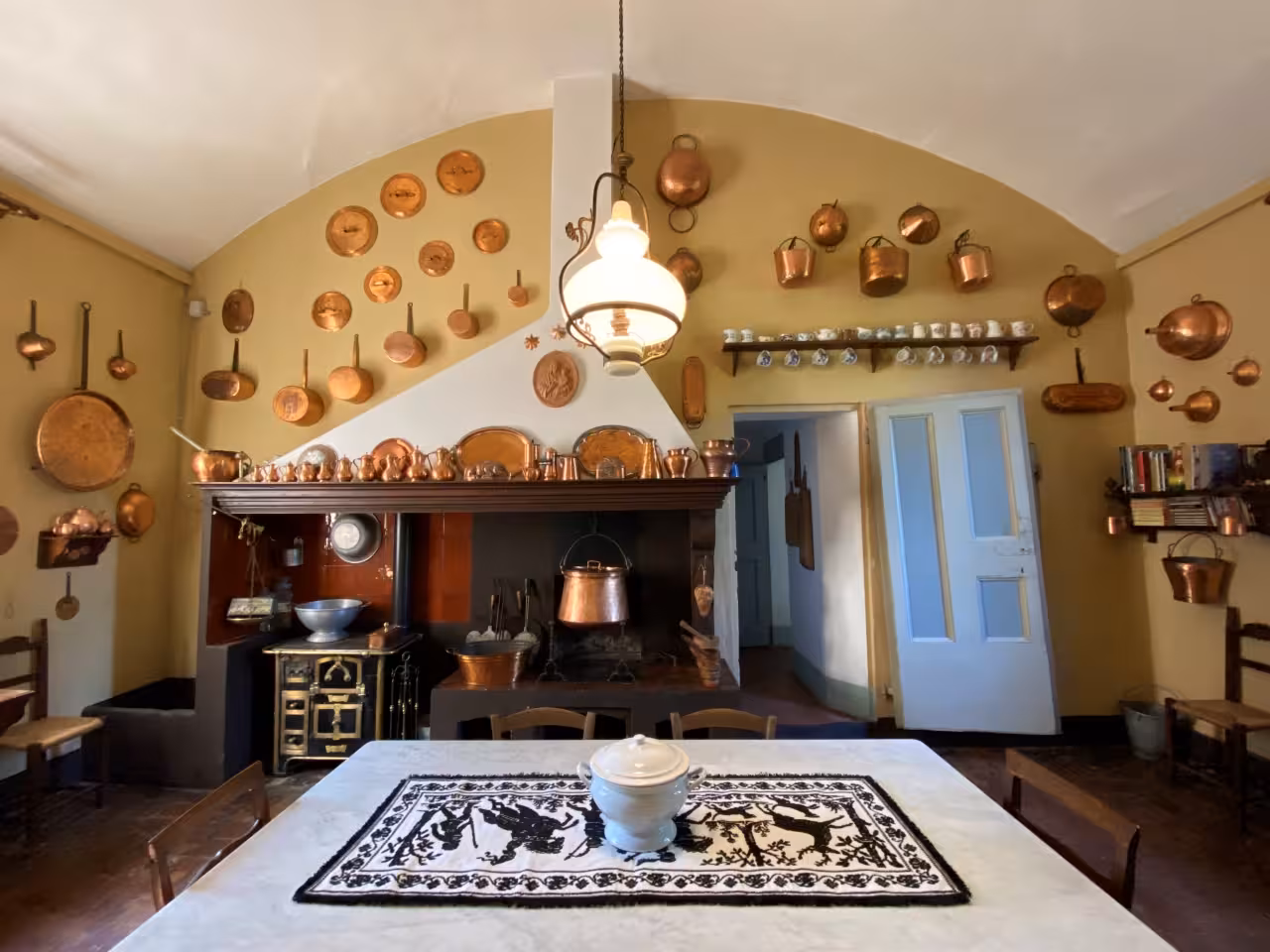 Historic Casa Museo NENA kitchen in Bologna with copper pots and hearth, featured on charming guided tour