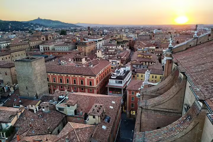 Sunset view over Bologna’s terracotta rooftops and medieval skyline, seen from a tower on a private 2-hour walking tour