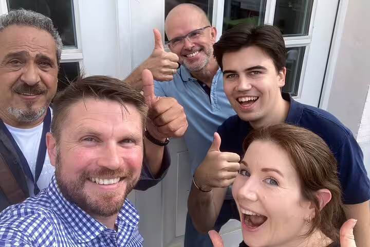 Happy group selfie giving thumbs up during Bonn scavenger hunt, self-guided city sights tour experience