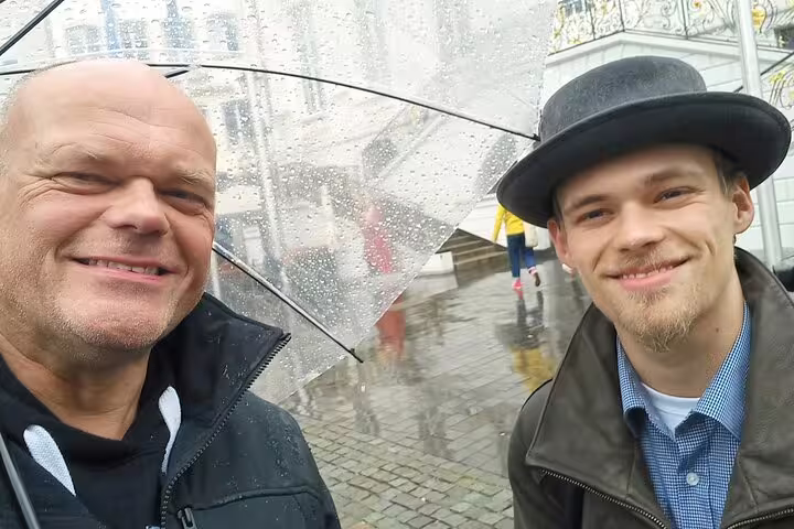 Smiling travelers in rainy Bonn with umbrella, exploring on a self-guided scavenger hunt city tour