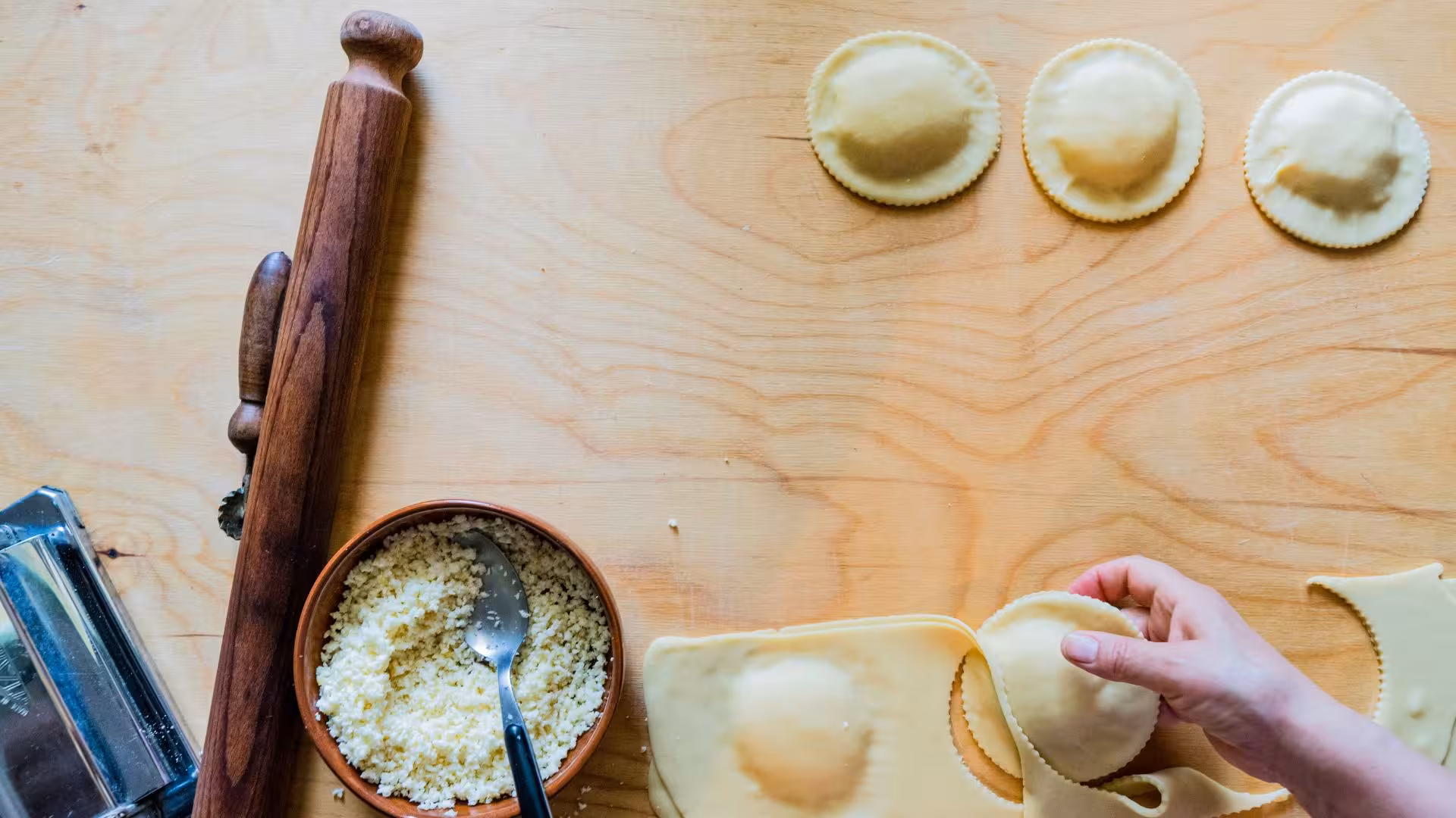 Close-up of hands preparing traditional seadas pastry with cheese filling in Bonorva workshop.