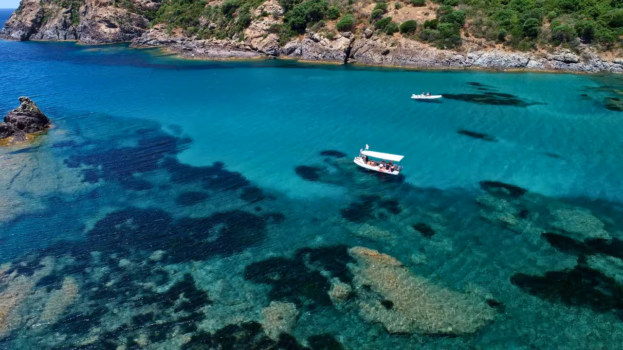 Aerial view of boats in the turquoise waters of Capo Marrargiu, Bosa, ideal for snorkeling and coastal exploration.
