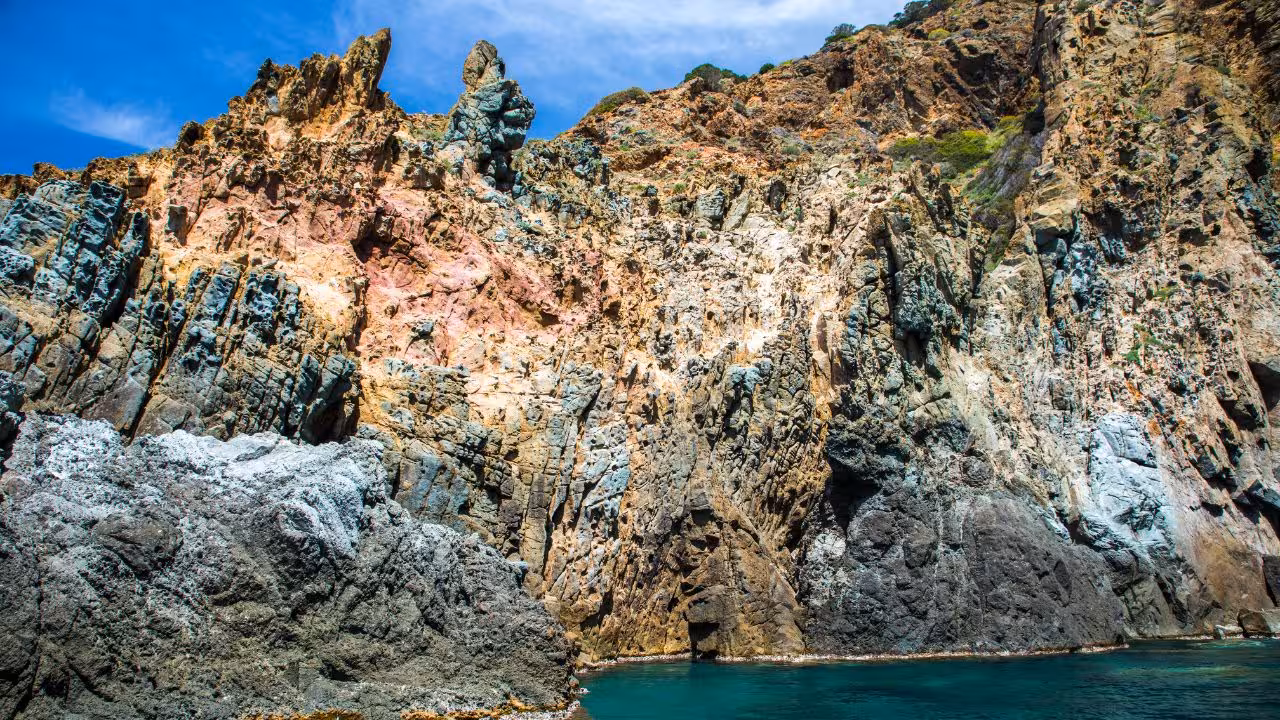 Dramatic cliffs of Capo Marrargiu rise above turquoise waters, ideal for snorkeling in Bosa's stunning coastal landscape.