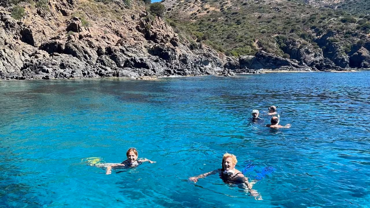 Snorkelers enjoy crystal-clear blue waters surrounded by rugged cliffs at Capo Marrargiu, Bosa's premier snorkeling spot.