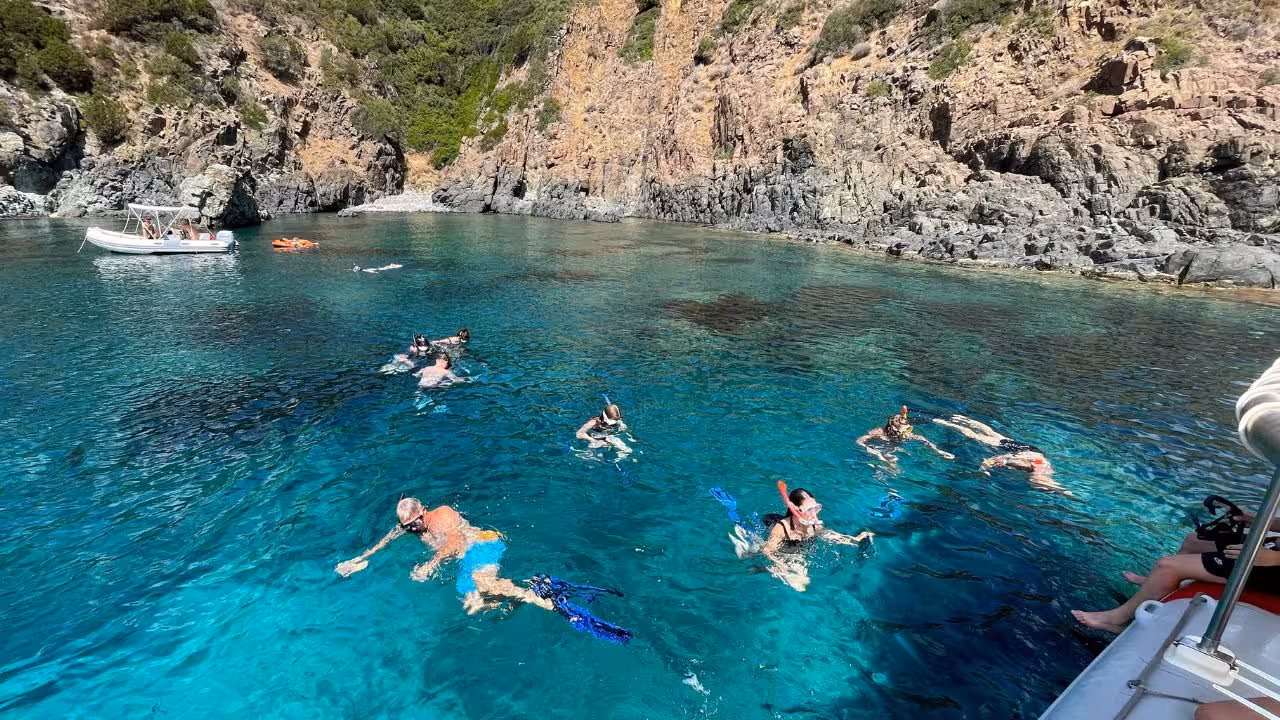 Snorkelers enjoy the crystal-clear waters of Capo Marrargiu in Bosa, surrounded by rugged cliffs and vibrant marine life.