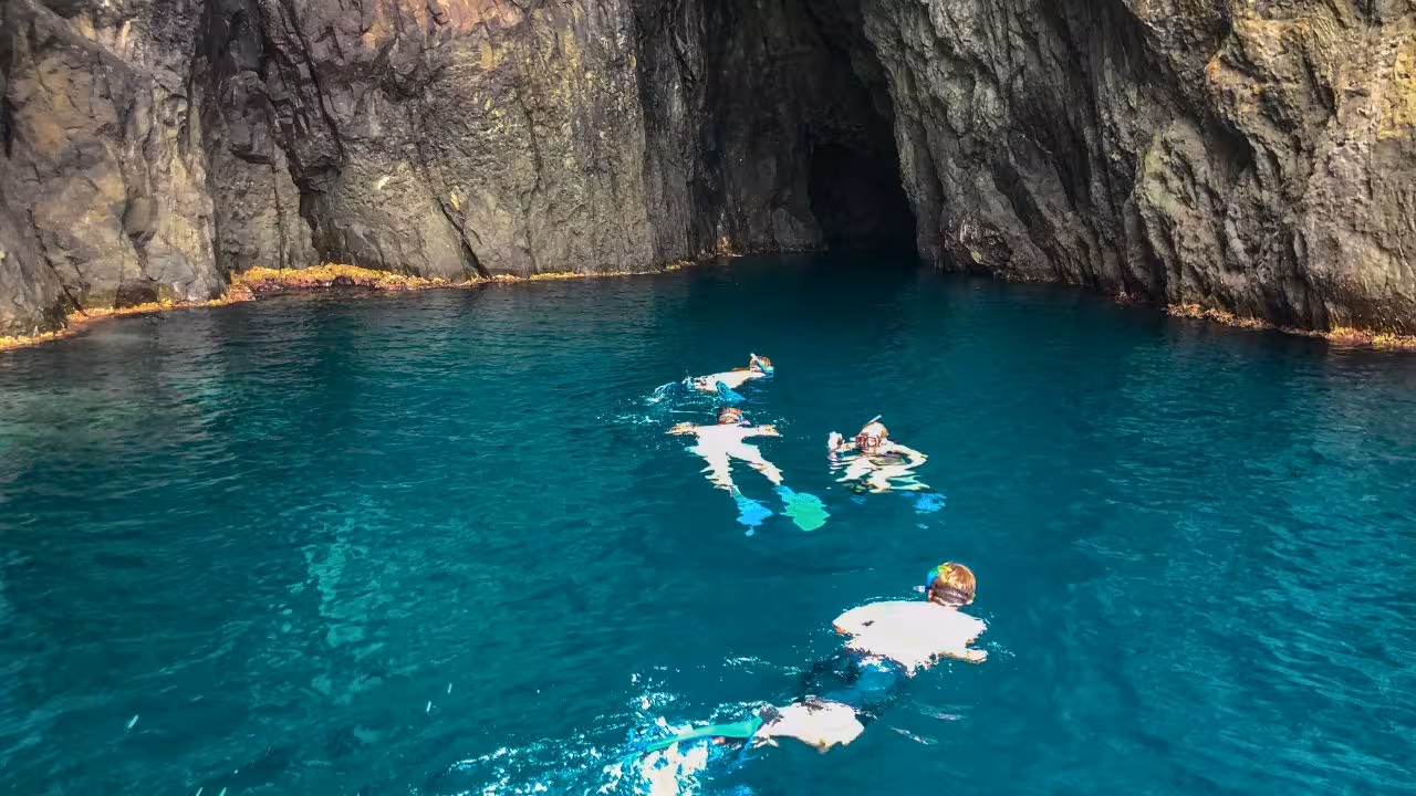 Snorkelers explore the crystal-clear waters and rocky caves of Capo Marrargiu in Bosa, Sardinia.