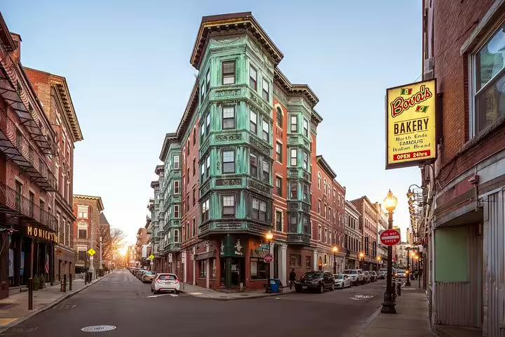 Historic North End Boston street corner with green copper bay windows building and Bova's Bakery sign at sunset