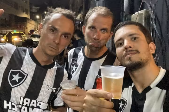 Friends in Botafogo black-and-white shirts toasting beers in Rio de Janeiro before joining a live match