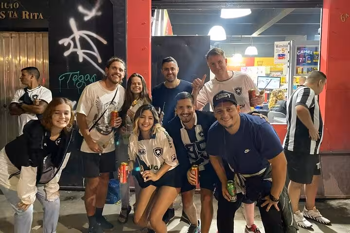 Botafogo fans with locals holding drinks outside a Rio bar before the soccer game experience near the stadium