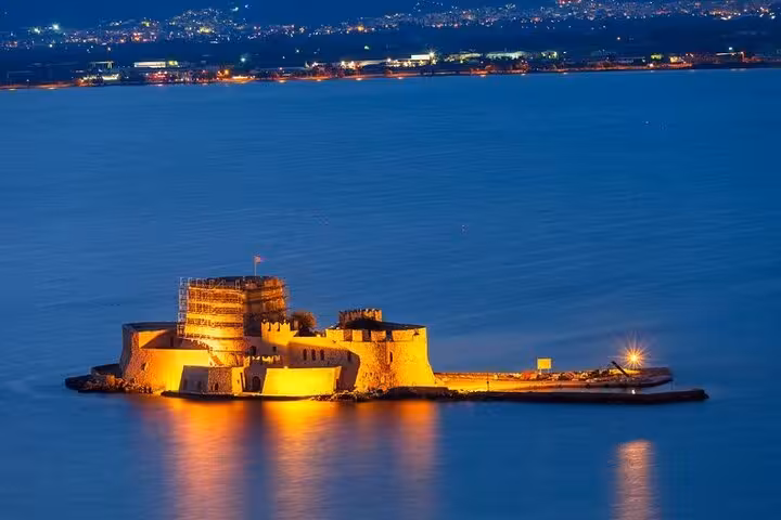 Illuminated Bourtzi Castle in Nafplio harbor at dusk, highlight of a private Nafplio day trip from Athens